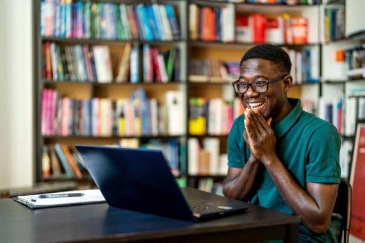 Happy young black male student in a library 