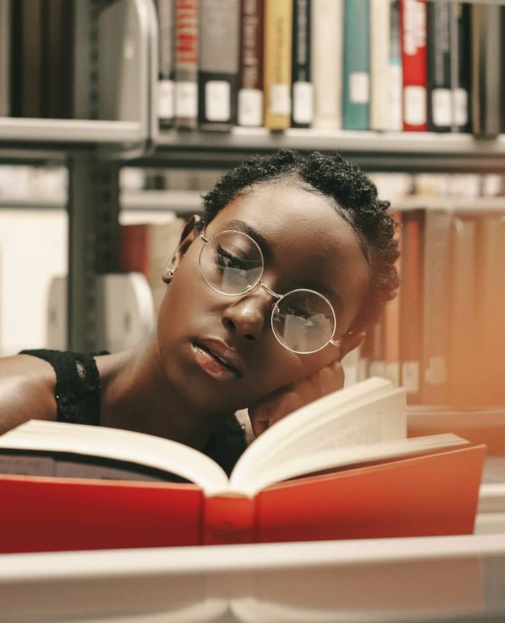 Young black lady with a book in a library 