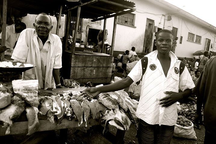 a man standing infront of  a meat seller