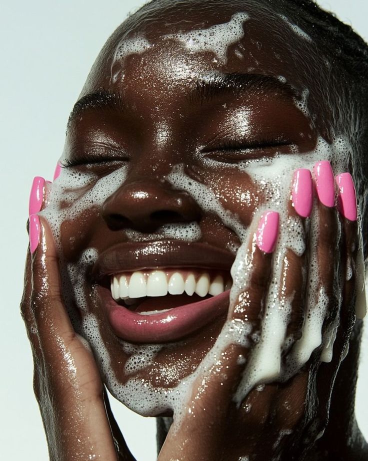 darkskinned woman washing her face with a cleanser