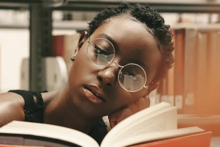 Young black lady with a book in a library 