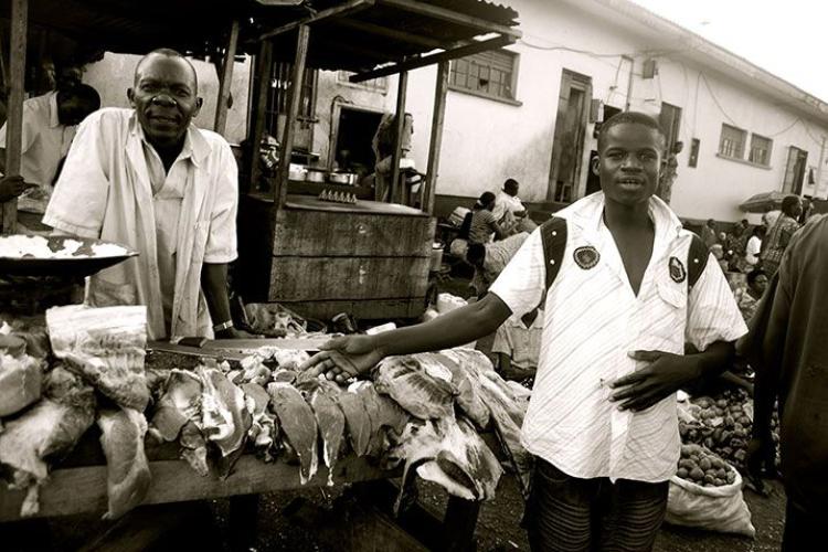 a man standing infront of  a meat seller