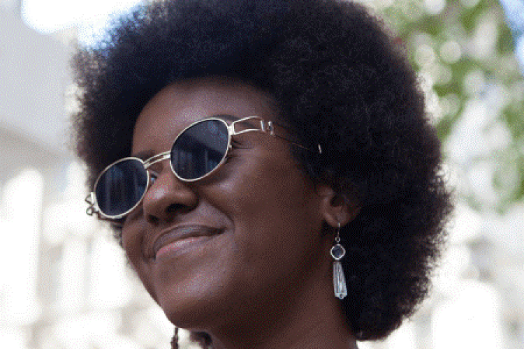 a darksinned woman with afro hair wearing glasses