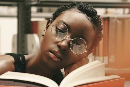 Young black lady with a book in a library 