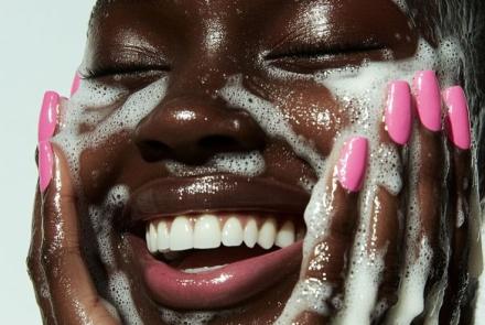 darkskinned woman washing her face with a cleanser